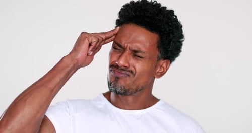 Man Rubs Temple in Frustration Against White Backdrop