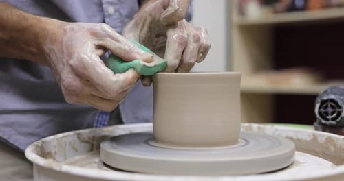 Potter Shaping Clay Vase on Wheel in Studio
