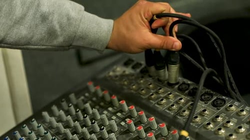 A man connecting a cable to the audio mixer - close up