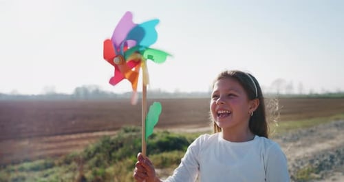 Authentic shot of cute little girl carefree having fun and blowing a colorful pin wheel.