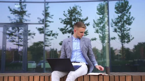 Man Working on Laptop, Takes Phone Call Outside