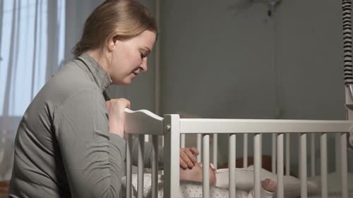 Young Mother Bonding with Infant in Crib