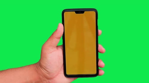 Man operating mobile phone with yellow display on a green background. Green screen chroma key.