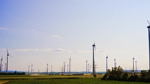 Wind turbines and power transmission towers in the vast fields. Green energy generation concept.
