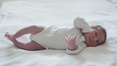 Cute Infant Lying on a Soft White Blanket
