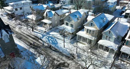 American town in fresh winter snow. Aerial establishing shot on sunny day. Road not clear, plowed. C