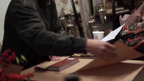 Person Wrapping Book with Craft Paper at Table