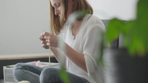 Woman Crocheting with Yarn at Home on Couch