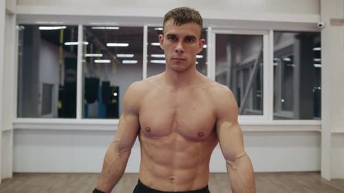 Portrait of a Young Muscular Man with a Naked Torso Who is Goes Through the Gym and Wipes His Face