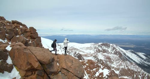 Couple on Rocks High Above Rocky Mountains, Dangerous Hike Adventure