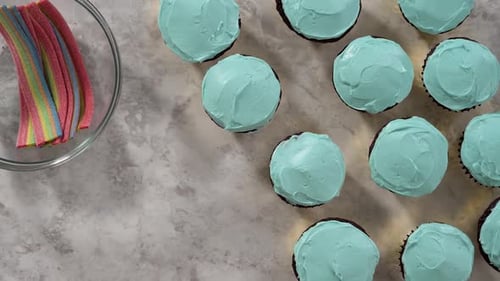 Flat Lay Decorating Chocolate Cupcakes with Buttercream Frosting and Rainbow Candy