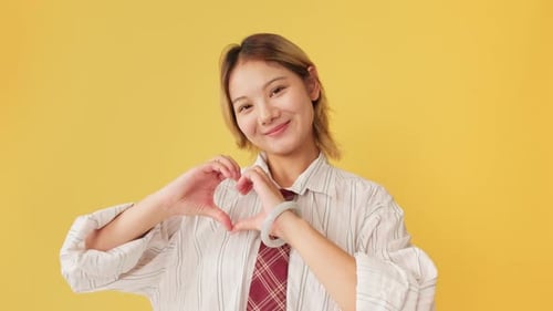 Young Adult Smiles and Makes Heart Shape