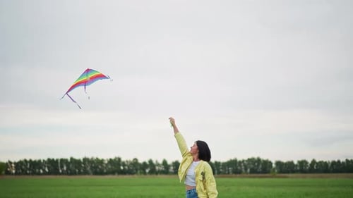 Woman Flying Colorful Kite in Open Grassy Field