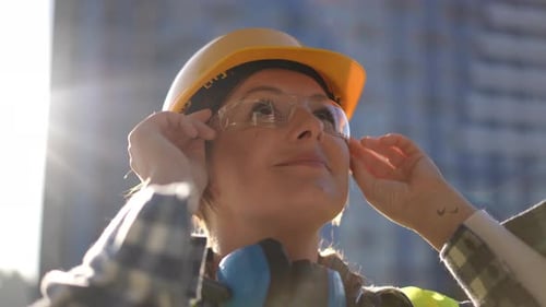 Woman Putting on Safety Glasses with Hard Hat