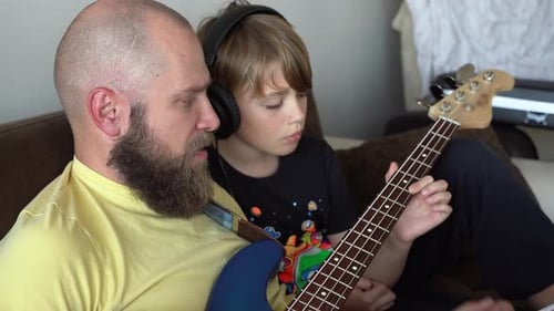 Man Teaches Child to Play the Guitar