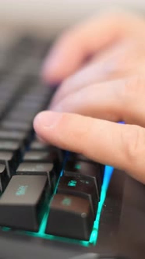 Hands Typing on Colorful Backlit Computer Keyboard
