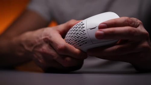 Closeup Unrecognizable Gamer Male Hands Turning on RGB Backlight on New Wireless Mouse Sitting at