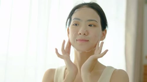 Young Woman Applying Face Sheet Mask