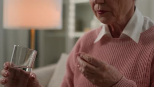 Senior Woman Taking Pill With Water at Home