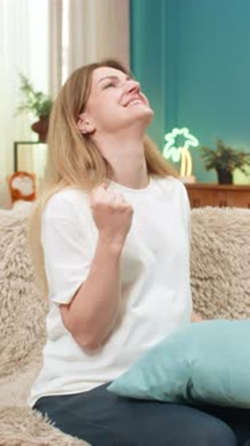 Woman on Couch Squeezing Pillow and Smiling