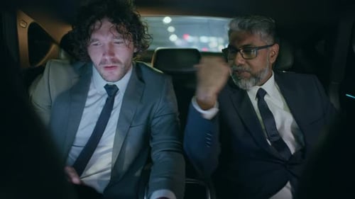 Geschäftskollegen diskutieren nachts im Auto über Informationen auf dem Laptop