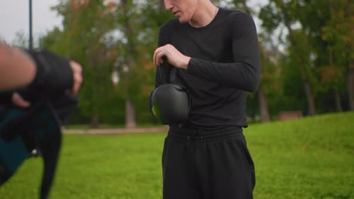 Man Putting on Boxing Gloves in an Urban Park