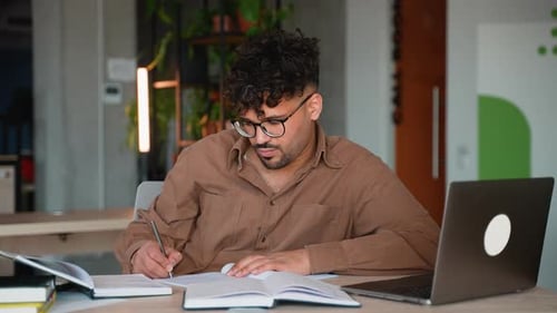 Adult Writing at a Desk with Laptop
