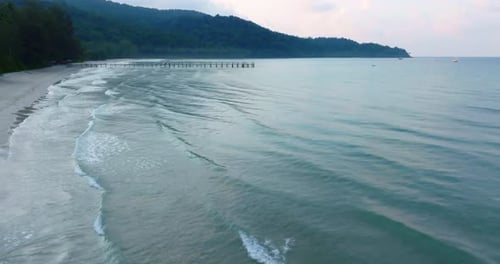 Aerial drone view of the tropical beach with clear turquoise sea, white sand and palm tree