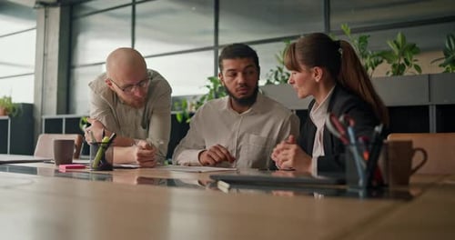 An Office Worker Participates in a Discussion with Colleagues Analyzing a Report and Finding