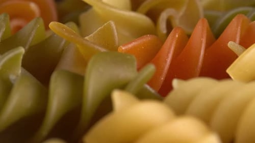 Pasta italiana multicolor Fusilli o Rotini girando sobre fondo macro. Pasta de trigo duro