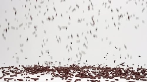 Brown chocolate sprinkles ice cream topping falling in slow motion and bouncing before settling into