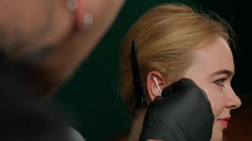 Close-up - male tattoo artist disinfects ear before piercing