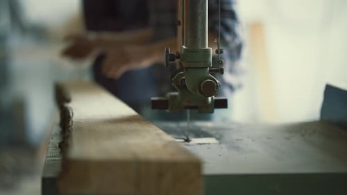 Carpenter Using Band Saw to Cut Wood Plank