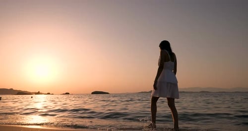 Woman Walks on Beach at Sunset