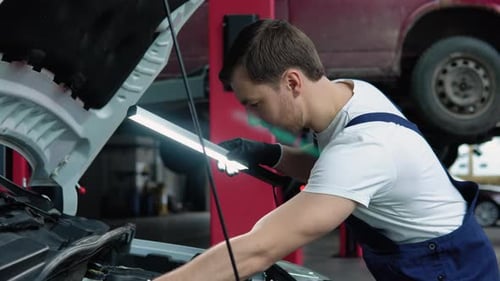 Car Service Repair Maintenance and People Concept Auto Mechanic Man with Lamp Working at Workshop