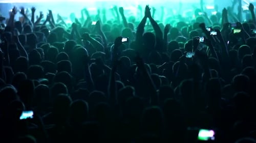 Fans waving their hands and filming by phones crowd at a concert partying at a night club with DJ pe