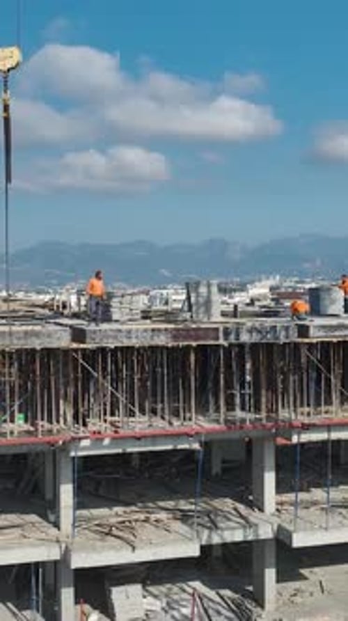Grabación vertical de un trabajador manipulando materiales de construcción en una plataforma elevada
