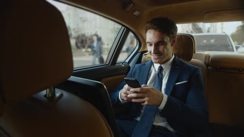 Smiling Businessman in Car Using Smartphone