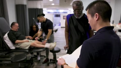 Physical Therapist with Medical Record Talking to Patient in Clinic 2529 Years
