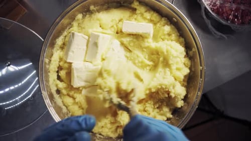 A Man in the Kitchen Stirs Butter Into Boiled Potatoes in a Saucepan