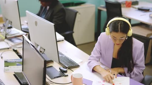 Woman Writes at Desk in Modern Office Setting