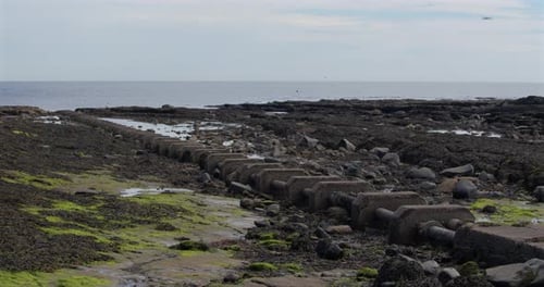 extra wide shot of sewage pipe going out to sea at low tide