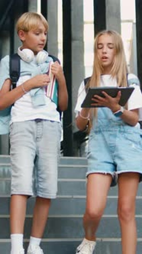 Zwei Freunde von Studenten im Teenageralter nutzen digitalen Tablet-Computer und tauschen Vorlesungen in der Nähe aus