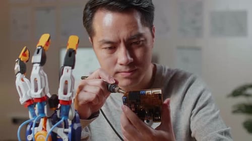 Close Up Of Asian Male Holding And Fixing The Circuit Board While Repairing A Cyborg Hand At Home