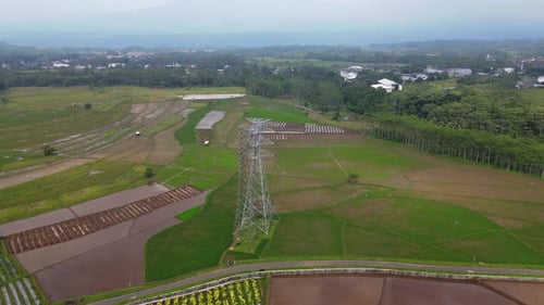 Bird eye drone shot of high voltage electricity tower on the middle of rice field - Asia