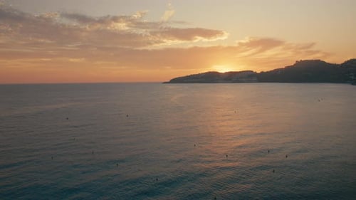 Magnifique coucher de soleil côtier orange chaud sur une mer calme et des collines silhouettées
