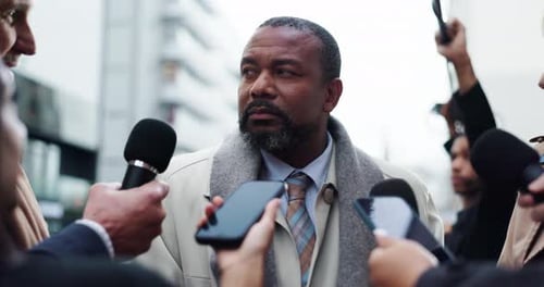 Man Giving a Press Conference Surrounded by Reporters