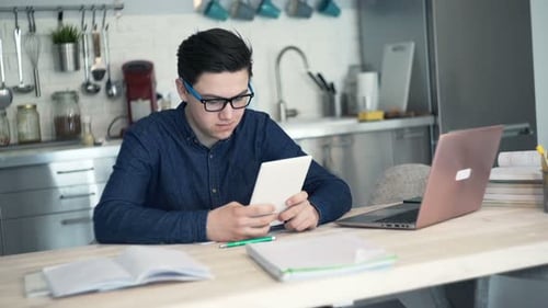 Teen Using Tablet and Laptop in Kitchen