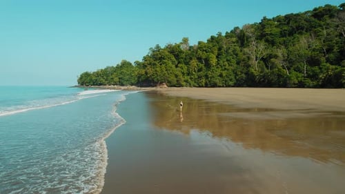 Woman running on a remote sandy tropical beach on a sunny day in Costa Rica