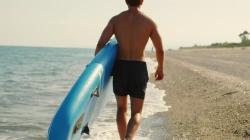 Man with Paddle Sup Board on the Beach